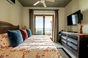 A hotel room with a bed, a TV, a dresser, and a balcony with a view.