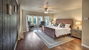 Um quarto com uma cama de madeira, uma mesinha de cabeceira, uma cadeira e uma escrivaninha.