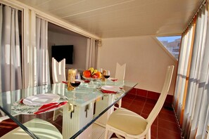 A dining area with a glass table, white chairs, and a view of the outdoors.