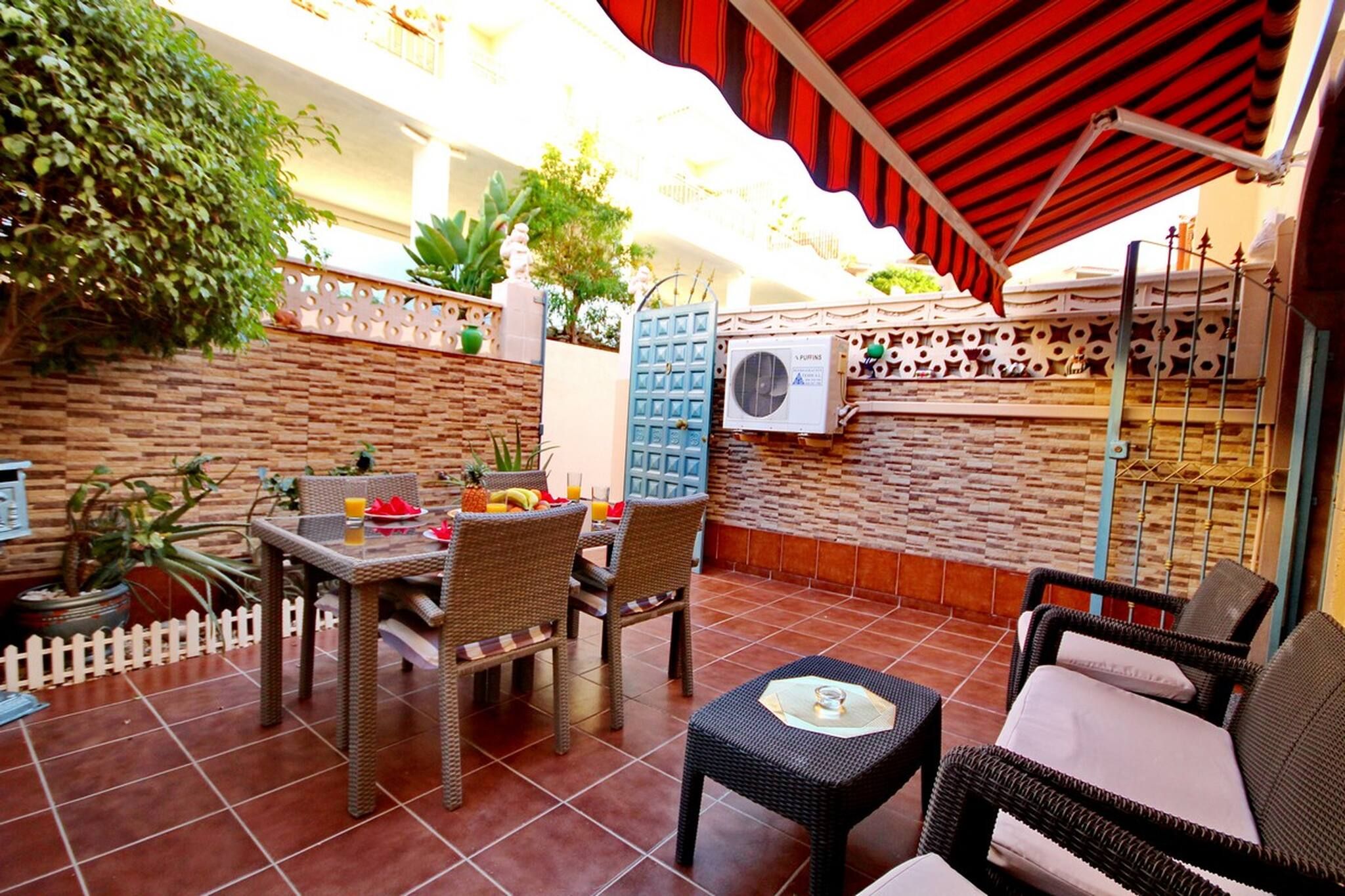 An outdoor patio with wicker furniture, a tiled floor, and a red awning.