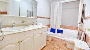 A bathroom with two sinks, a toilet, a bidet, and a bathtub.