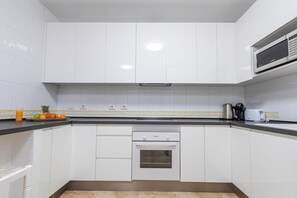 A kitchen with white cabinets, a built-in oven, a microwave, and a coffee maker on the countertop.