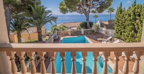 Ein Pool mit Blick aufs Meer, umgeben von Bäumen und einem Zaun.