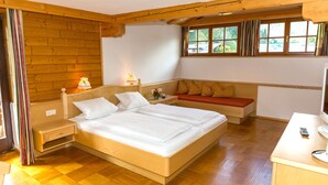 Ein Schlafzimmer mit einem hölzernen Bett, einem Nachttisch, einem Fernseher und einem Fenster mit Vorhängen.