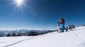 Eine verschneite Berglandschaft mit blauem Himmel und strahlender Sonne.