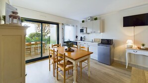 Een moderne keuken met een eethoek, een televisie en een schuifdeur naar een balkon.