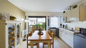 Een moderne keuken met een eethoek, met een houten tafel en stoelen, een inbouwoven en uitzicht op de omgeving.
