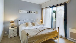 Een slaapkamer met een bed, nachtkastjes, een wandplank met foto's en een raam met gordijnen.