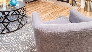 Un salon doté d’une cheminée en pierre, d’un téléviseur à écran plat fixé au-dessus, d’un ventilateur de plafond et offrant une vue sur l’extérieur grâce à une grande fenêtre.