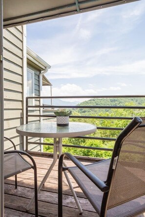 Un balcon avec une table ronde et deux chaises, donnant sur un paysage verdoyant et luxuriant.