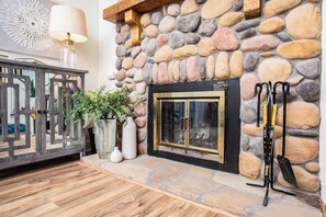 Cozy space with a stone fireplace, wooden cabinet, and ski equipment on display.