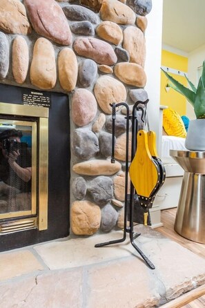 A fireplace is nearby, with a decorative item on a metal stand in front.