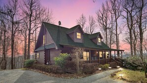 A log cabin with a porch, surrounded by trees. - Experience Luxury at The Sanctuary in Hendersonville (Hendersonville)