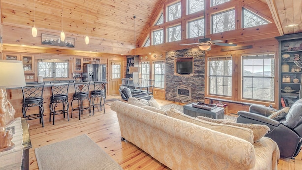 A spacious living area with a high ceiling, wooden beams, and large windows. - Experience Luxury at The Sanctuary in Hendersonville (Hendersonville)
