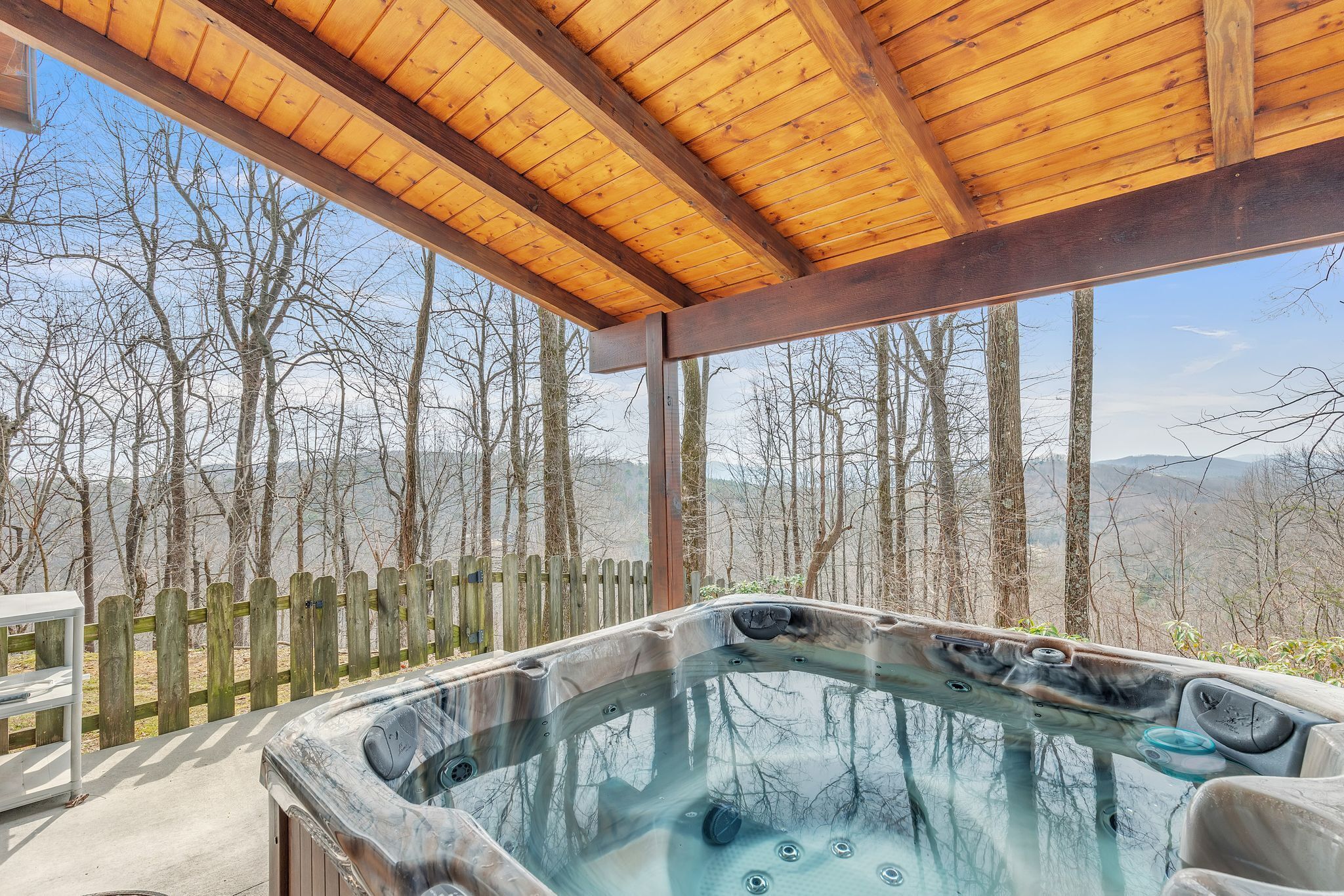 Un bain à remous doté d’un toit en bois et offrant une vue sur les arbres et les montagnes.
