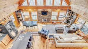 A spacious living area with a stone fireplace, wooden beams, and large windows. - Experience Luxury at The Sanctuary in Hendersonville (Hendersonville)
