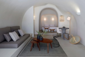 A modern living room with a sofa, coffee table, and a dining area with a table and chairs.