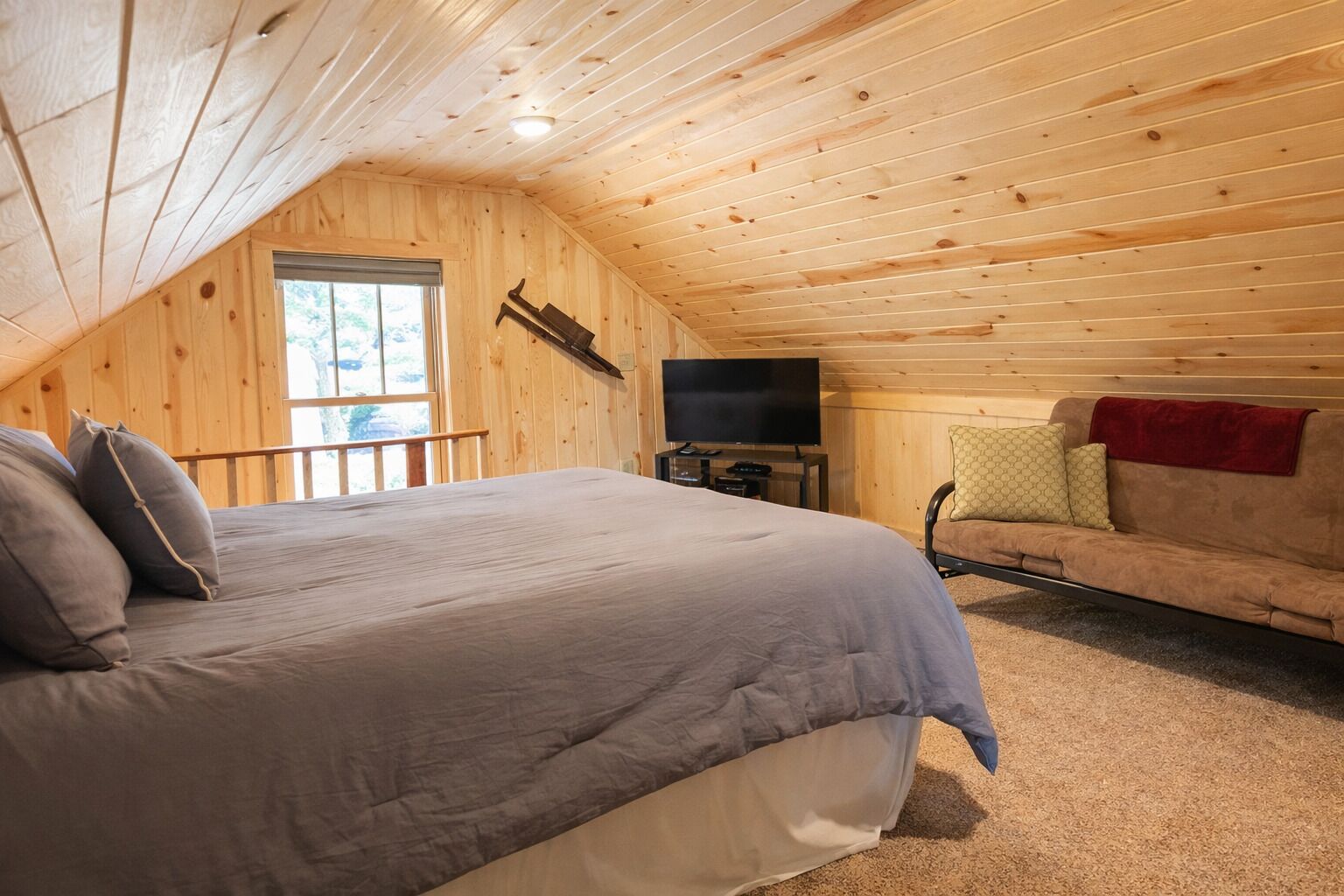 A cozy attic bedroom with a large bed, a TV, and a sofa.