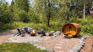 An outdoor seating area with a fire pit, Adirondack chairs, and a wooden barrel structure. - 8 Min to State Parks|Sauna|Fire Pit| (Beaver Bay)