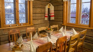 A wooden cabin interior with a dining table set for four, surrounded by wooden chairs.