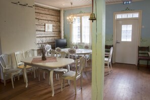 A dining area with a wooden table, white chairs, a television, and a chandelier.