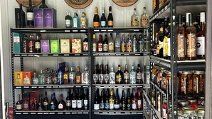 Une boutique de boissons alcoolisées dont les étagères sont remplies de bouteilles et de cartons de différentes sortes d’alcool.