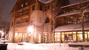 Un hotel de varios pisos con fachada de piedra, balcones y un suelo cubierto de nieve.