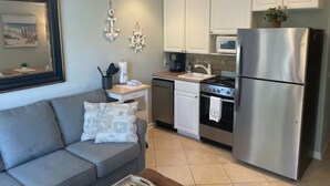 A compact kitchen with white cabinets, a stainless steel refrigerator, a microwave, and a stove. - BEACHFRONT KING BED VILLA, PRIVATE BALCONY, SELF CHECKIN, FLEXIBLE CANCELLATION (Hilton Head Island)