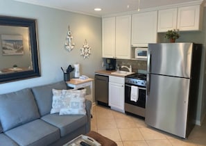 A compact kitchen with white cabinets, a stainless steel refrigerator, a microwave, and a stove.