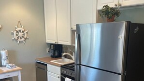 A modern kitchen with white cabinets, a stainless steel refrigerator, a dishwasher, and a stove. - BEACHFRONT KING BED VILLA, PRIVATE BALCONY, SELF CHECKIN, FLEXIBLE CANCELLATION (Hilton Head Island)