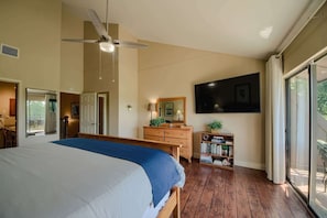 Una camera da letto con un letto, una ventola a soffitto, una cassettiera, una televisione e una libreria.