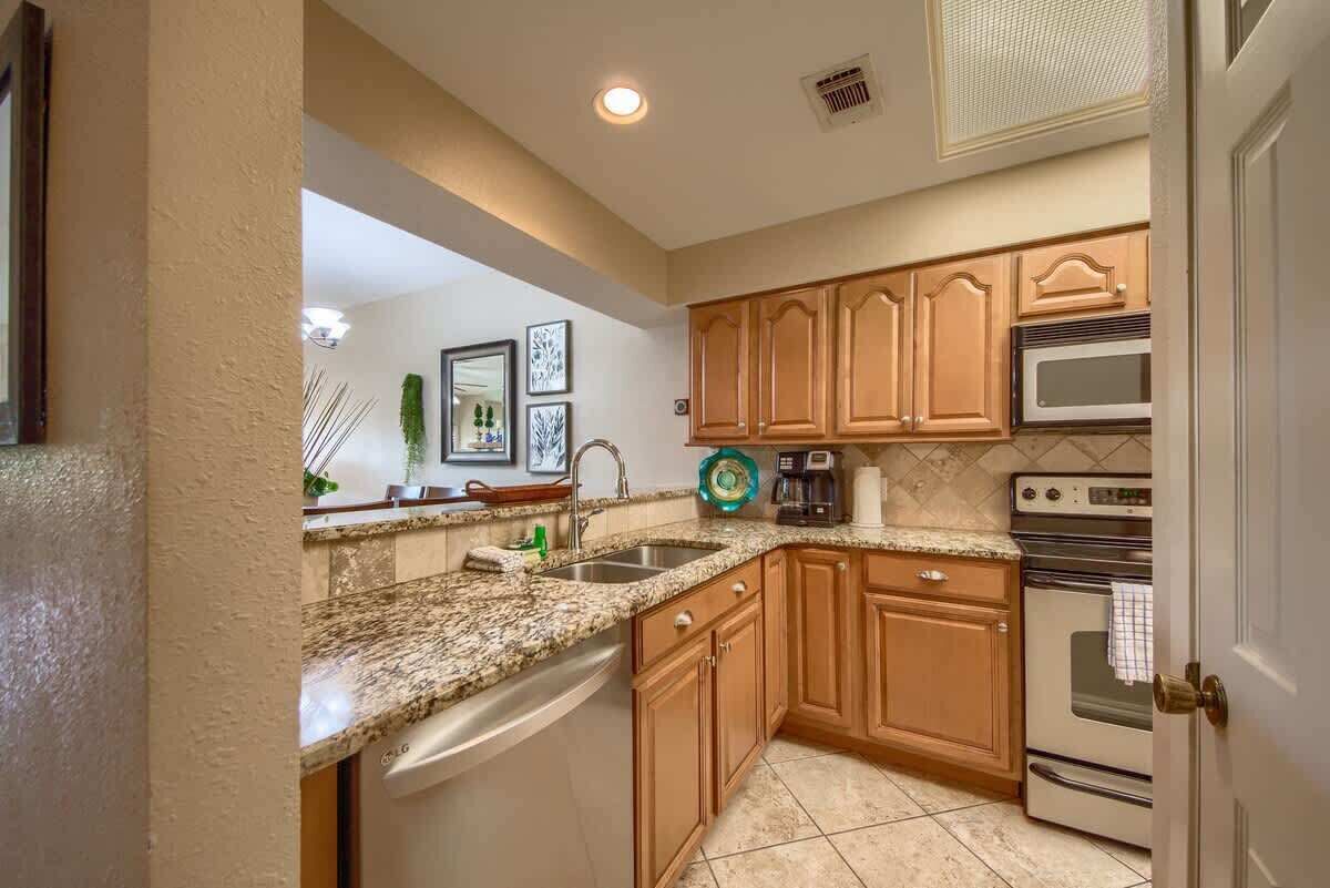 A kitchen with wooden cabinets, a granite countertop, a dishwasher, a microwave, and an oven.