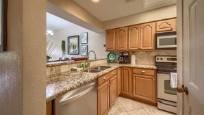 A kitchen with wooden cabinets, a granite countertop, a dishwasher, a microwave, and an oven.