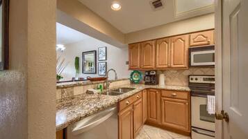 A kitchen with wooden cabinets, a granite countertop, a dishwasher, a microwave, and an oven.
