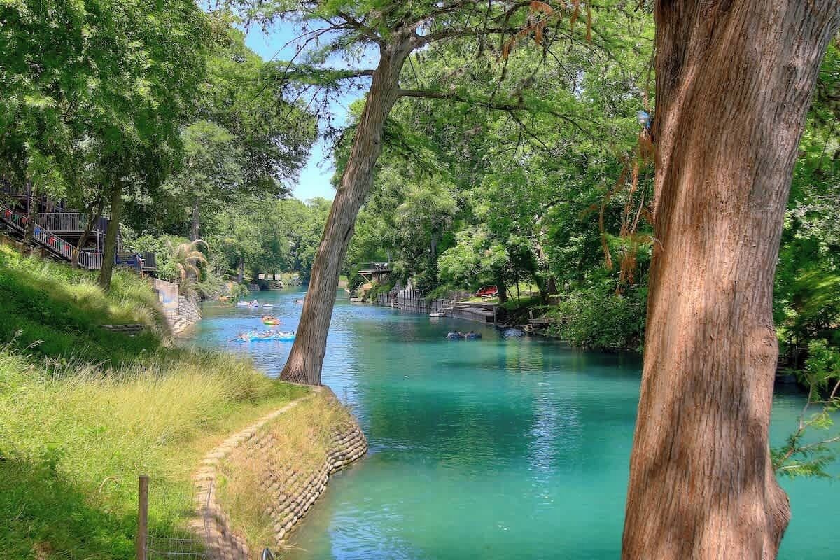 Une rivière bordée d’arbres, avec un sentier qui la longe.