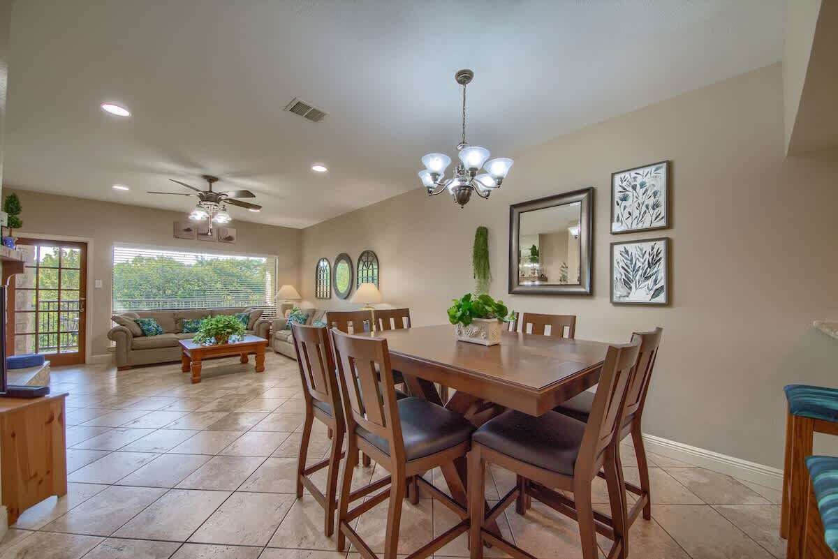 A dining area with a large wooden table, chairs, a chandelier, and artwork on the walls.