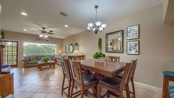 A dining area with a large wooden table, chairs, a chandelier, and artwork on the walls.