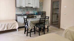 Une cuisine compacte avec un coin repas, comprenant une petite table avec des chaises, un réfrigérateur et un évier.