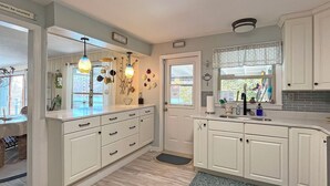 A kitchen with white cabinets, a wooden countertop, a sink, and a window with a view of greenery.