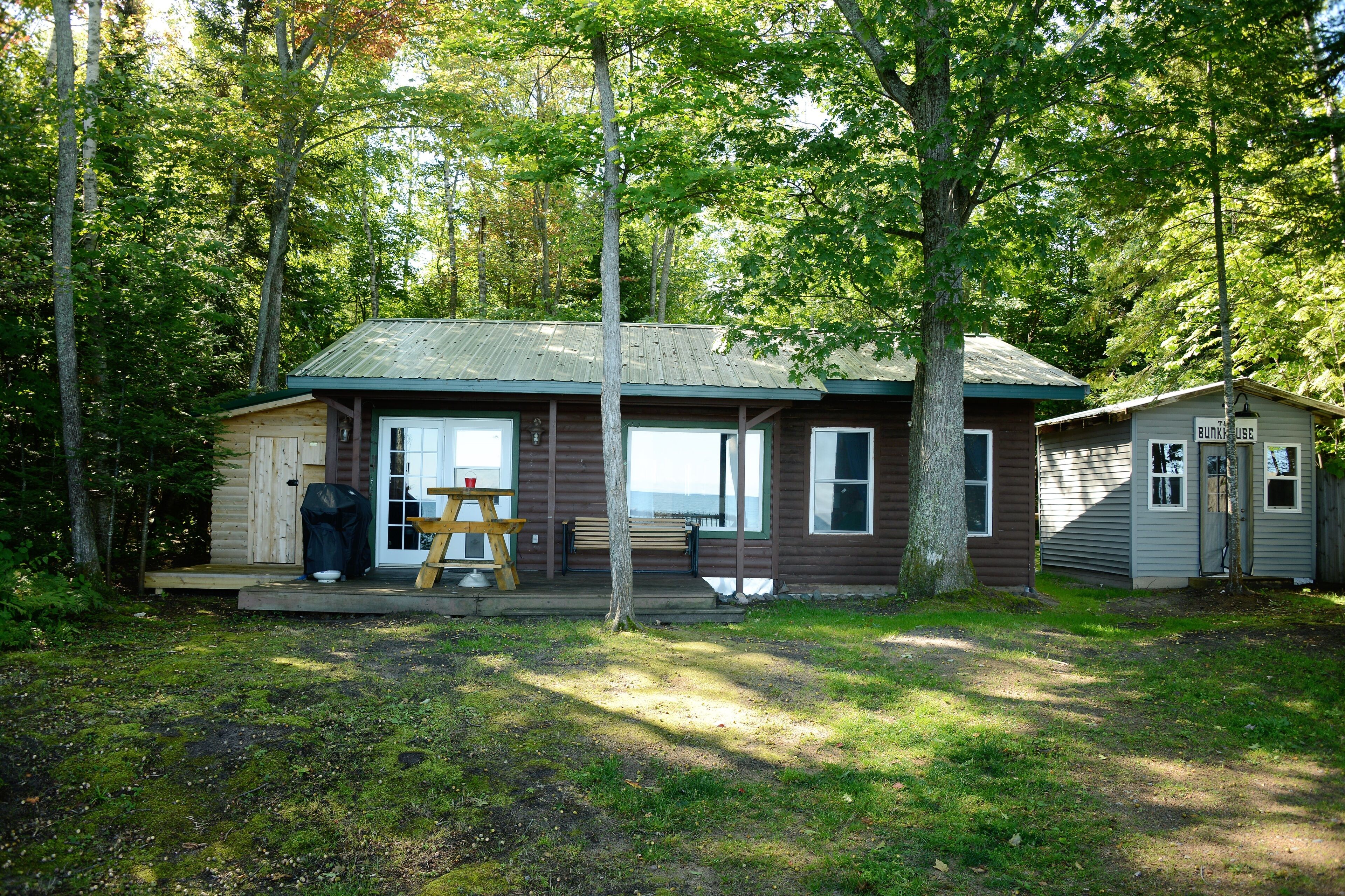Une cabane avec une véranda, une table de pique-nique et un espace abrité.