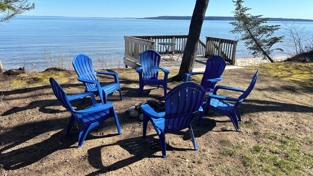 Une terrasse au bord du lac, avec des chaises Adirondack bleues et une zone de terrasse en bois.