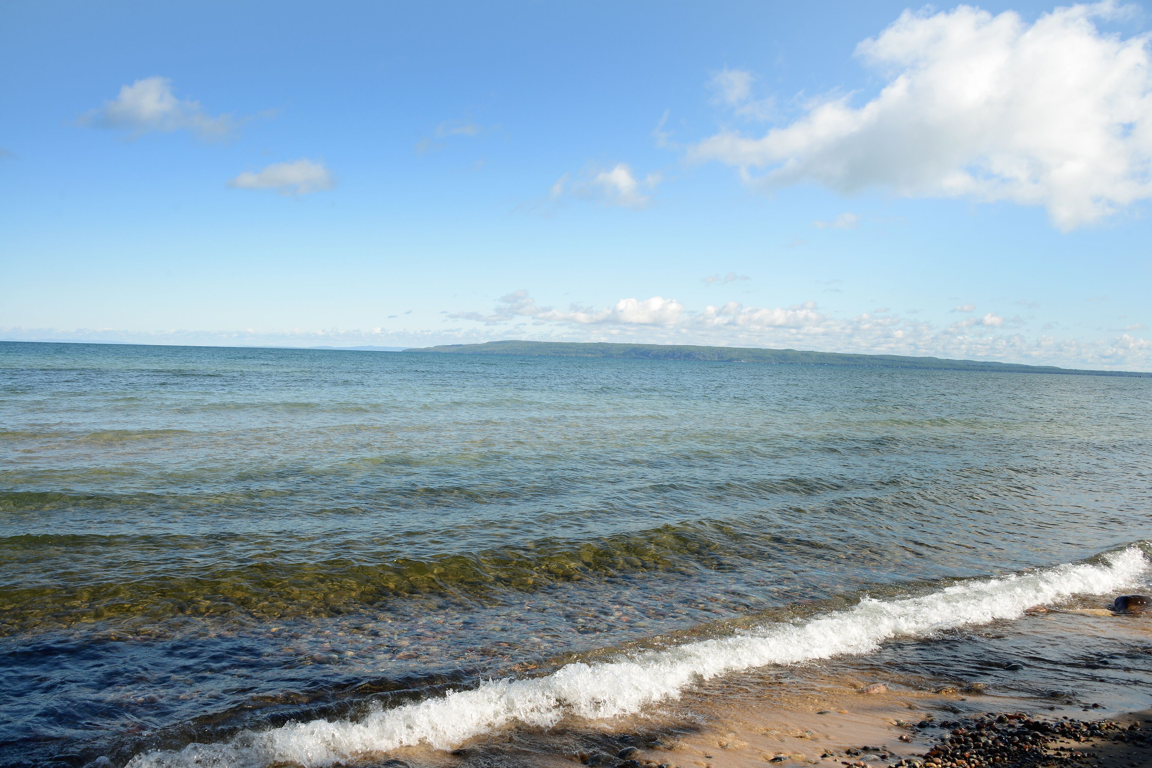 A beach with clear water and a distant shoreline.