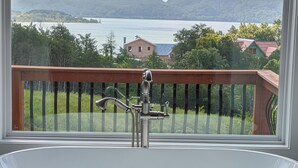 A bathtub with a view of a lake and mountains through a window. - Like New Lake & Mountain Views from every room in the house! (Dandridge)