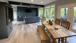 A modern kitchen with a dining area, wooden flooring, and large windows offering a view of the outdoors. - Like New Lake & Mountain Views from every room in the house! (Dandridge)