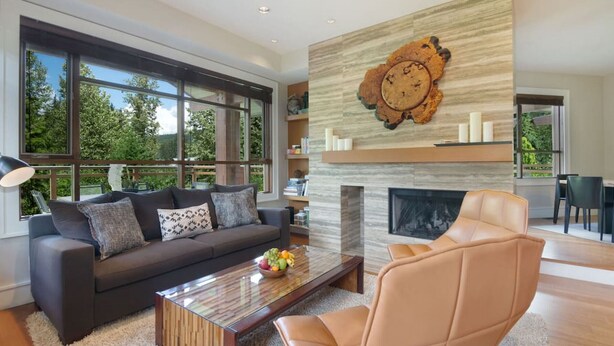 Una sala de estar moderna con un ventanal grande, una chimenea y un sillón de cuero.