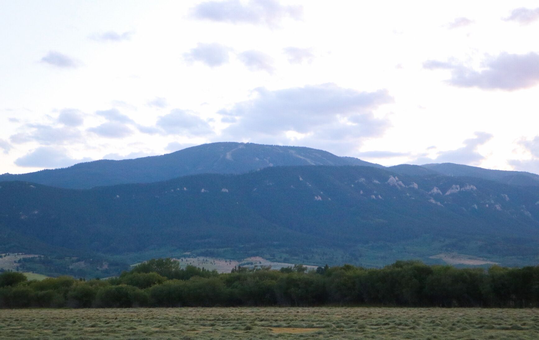 A mountainous landscape with a field in the foreground and a range of hills in the background.