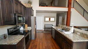 Une cuisine moderne avec des meubles en bois foncé, des appareils électroménagers en acier inoxydable et un plan de travail en marbre.