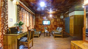 A wooden-paneled room with a desk, two chairs, a television, and a wardrobe. - Hello we are greeting from royal stay jaisalmer  (jaisalmer india)