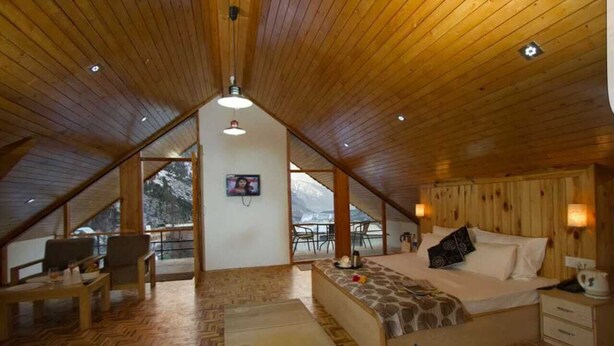 A cozy attic bedroom with a wooden ceiling, a bed, a desk, and a view of snowy mountains. - Hello we are greeting from royal stay jaisalmer  (jaisalmer india)