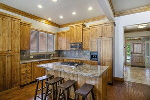 Enjoy cooking in this well-lit kitchen with a central island, stainless steel stove, and wooden cabinetry.